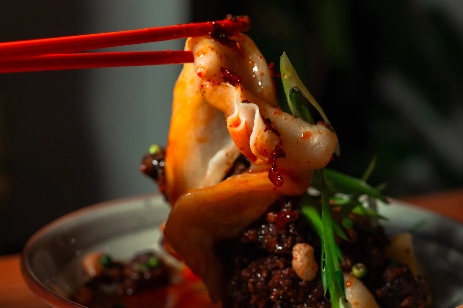 A diner lifting a dumpling with chopsticks