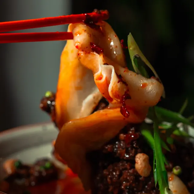 A filled dumpling lifted with chopsticks at Mirin