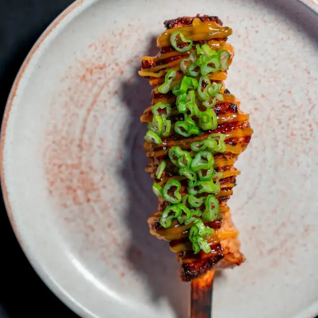 A glazed skewer topped with sliced green onion at Mirin